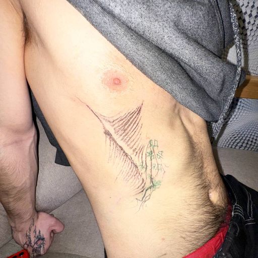 Тату на боку: перо с нотами и плющом